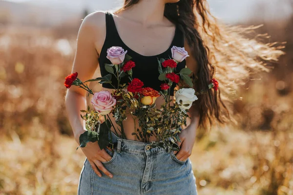 Joven hermosa mujer con el pelo largo en la naturaleza, diferentes tipos de flores en jeans, concepto de salud femenina, disfrutando del aire fresco —  Fotos de Stock