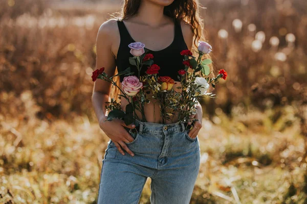 Joven hermosa mujer con el pelo largo en la naturaleza, diferentes tipos de flores en jeans, concepto de salud femenina, disfrutando del aire fresco —  Fotos de Stock