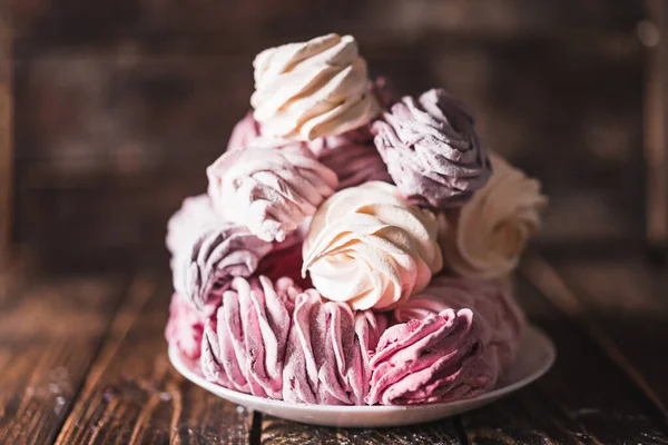 stock image Appetizing multi-colored marshmallow on a plate on a wooden table. Tea drinking concept. Confectionery decoration. Place for text