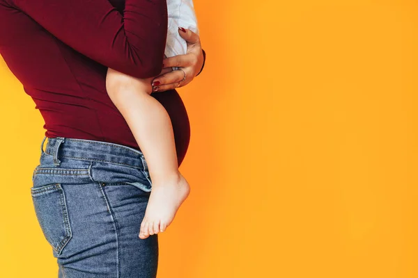 妊娠中の若い女性は黄色の背景の前で小さな赤ちゃんを抱えています 妊娠中の女性の健康管理 人工授精 — ストック写真
