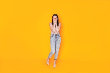 Sarı arka planda duran genç bir kadın. Bir afiş için mükemmel bir reklam fotoğrafı. Sağlık hizmetleri. Evde makyajını kendin yap..