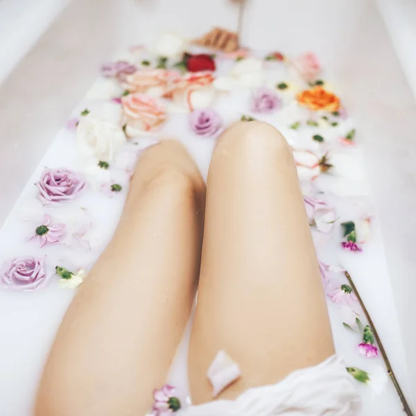这个女人洗了个充满牛奶的健康浴 五颜六色的玫瑰花蕾飘浮在水面上 放松和抗衰老治疗 — 图库照片