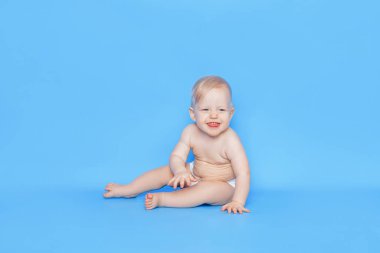 Küçük bir çocuk mavi arka planda oturuyor. Küçük çocukların sağlığıyla ilgilenmek..