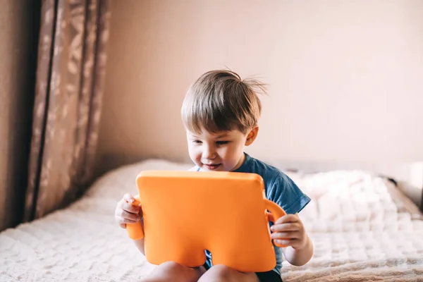 Menino Está Sentado Cama Segurando Tablet Suas Mãos Aprendizagem Distância — Fotografia de Stock