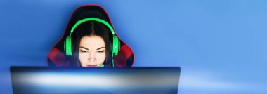 Oyuncu bir oyun sandalyesine oturur ve bilgisayar oyunları oynar. Oyuncunun kafasında yeşil kulaklık var.