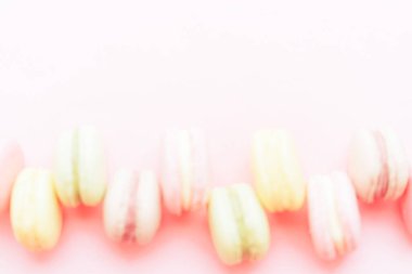 Farklı renklerde makarnalar pembe arka planda bir sırada yatar. Sevdiğin biri için bir hediye. Her durum için lezzetli bir tatlı..