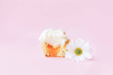 Güzel, iştah açıcı, beyaz bir kek. Pembe arka planda bir çiçeğin yanında ikiye bölünmüş. Herhangi bir şenlik masası için tatlı.