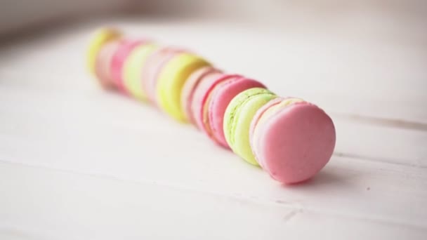 Macarony různých barev stojí v řadě na dřevěném bílém pozadí. Dárek pro 14 únor, 8. březen, Den matek — Stock video