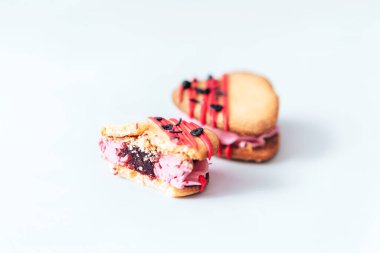 Kalp şeklinde kekler beyaz arka planın ortasına yerleştiriliyor, bir pasta ısırılıyor. Tatil için ev yapımı kekler, parti ve sevdiğine hediye.