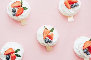 Beyaz ve böğürtlen kremalı lezzetli hamur işleri pembe arka planda duruyor..