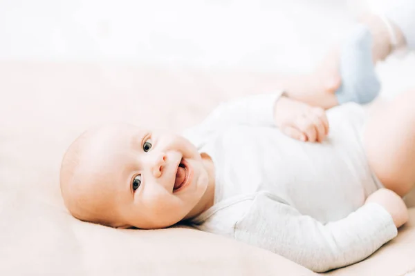 Bebé recién nacido riendo acostado en la cama. El cuidado de los niños recién nacidos — Foto de Stock