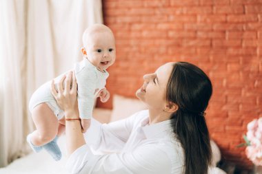 Genç anne yeni doğmuş bebeğini kollarında tutuyor. Çocuklara sevgi ve ilgi.
