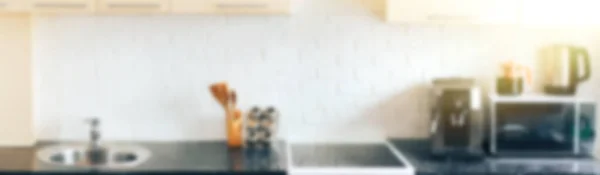 Light kitchen design, white brick apron. Kitchen appliances on a black marble counter. Long banner with sun glare.