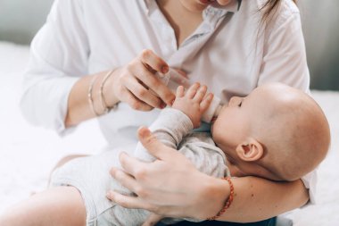 Bakıcı anne şişesi yeni doğmuş bebeğini besler. Çocukların sağlığıyla ilgilenmek. Çocukların yapay beslenmesi.