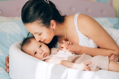 Genç bekar anne melez bebeğini öpüyor. Çocuk evlat edinme ve tüp bebek. Asyalı bebek ve Hintli anne.