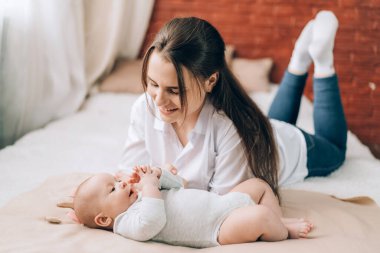 Genç bekar bir anne karantina sırasında bebeğiyle yatakta oynar. Çocuk evlat edinme ve tüp bebek. .