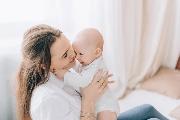 Genç anne yeni doğmuş bebeğini kollarında tutuyor. Çocuklara sevgi ve ilgi.
