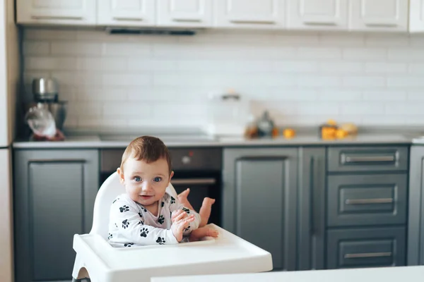 Liten pojke sitter i stol för spädbarn i modernt grått kök — Stockfoto