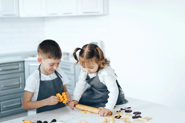 Kinder bereiten Plätzchen mit Süßigkeiten zu, ein Junge rollt den Teig mit dem Nudelholz aus. Freizeitaktivitäten mit Kindern — Stockfoto