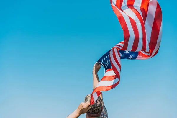 Man i militär uniform håller amerikansk flagga över klar himmel — Stockfoto