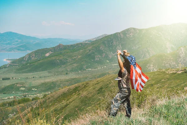 Чоловік з дитиною на шиї, хлопчик на спині має американський прапор перед горами. — стокове фото