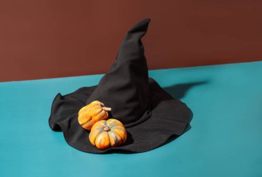 Mavi arka planda balkabakları olan siyah cadı şapkası..