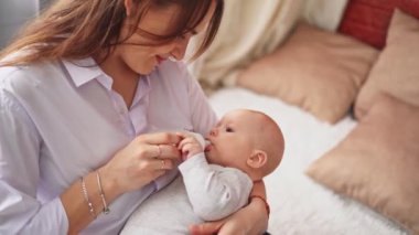 Anne yatak şişesinde oturup bebeğini besliyor.