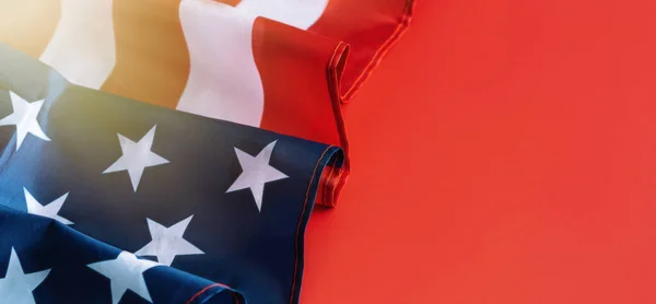 Amerikansk flagga vikta i våg på röd bakgrund med solsken. Begreppet självständighetsdag, lång banderoll — Stockfoto