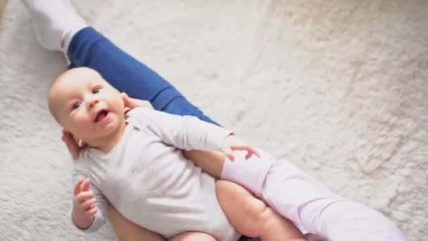Joven madre sacude a su bebé en sus brazos y juega — Vídeos de Stock