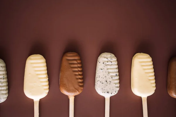 Линия молока и белого шоколадного мороженого на коричневом фоне, вид сверху. — стоковое фото