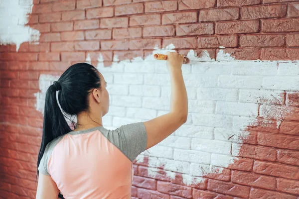Девушка Кистью Окрашивает Кирпичную Стену Белой Краской — стоковое фото