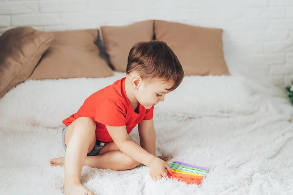 Küçük Çocuk Yatağın Üstünde Çocuk Oyuncağıyla Oynuyor — Stok fotoğraf