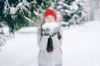 Kız ellerinden kar üflüyor. Kış Ormanı.