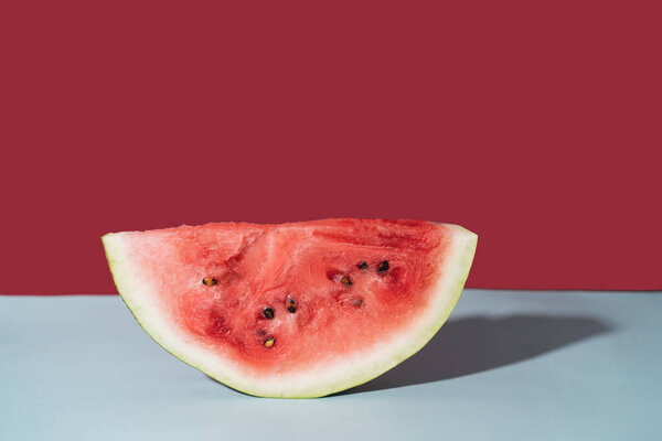 Piece of ripe watermelon against red background.