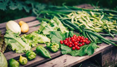 Taze toplanmış sebzeler ve böğürtlenler ahşap palette yatıyor..