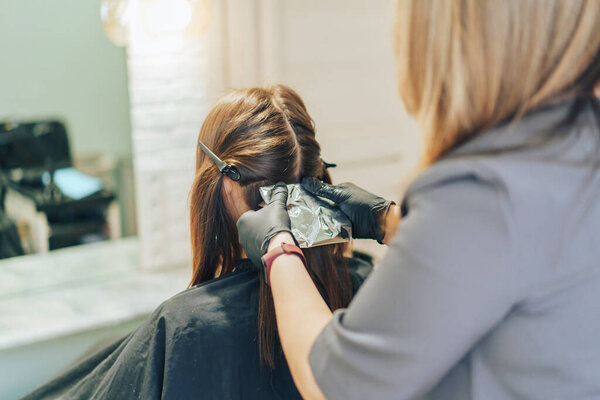 hair stylist dyes hair with a brush with foil.