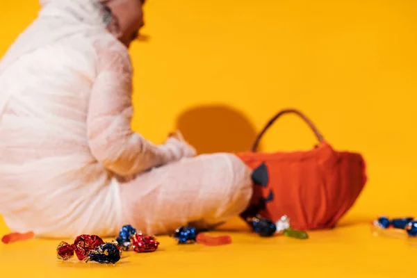 Criança Traje Múmia Come Balas Cesta Forma Abóbora Contra Fundo — Fotografia de Stock