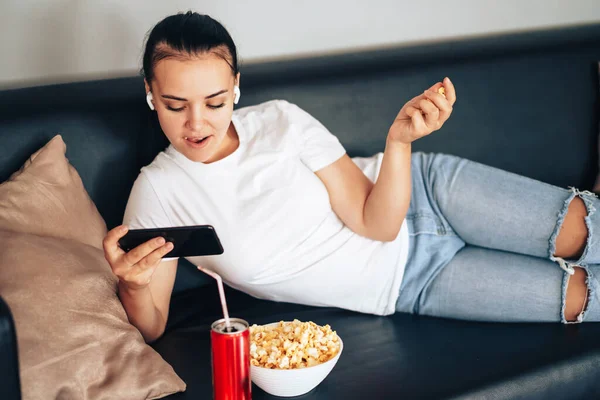 Girl watching e-sports stream with can of juice and popcorn