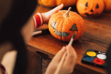 Korsan gibi giyinmiş çocuk balkabağına yüzünü çizmiş..