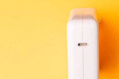 Sarı üzerine beyaz bir USB-C güç adaptörünün yakın çekim stüdyosu, modern hızlı şarj teknolojisi ve temiz ürün tasarımını ön plana çıkarıyor.. 