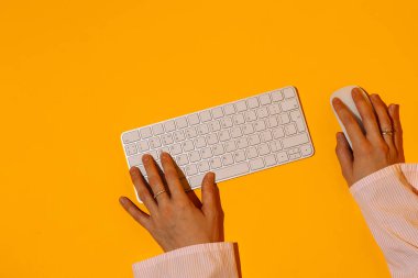 Eller turuncu arka planda klavye ve fare üzerinde yazıyor. Yüksek kalite fotoğraf