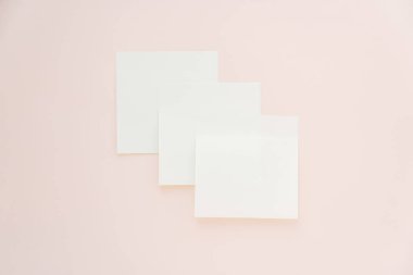 Pastel pembe arka planda üç boş yapışkan nota, minimum model.