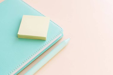 Yumuşak pastel çalışma alanına yapışkan notlar ve kalemle not defteri.