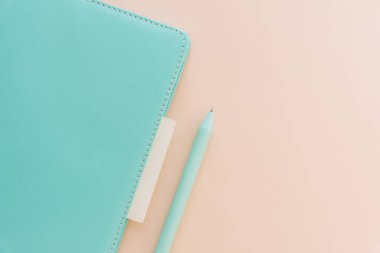 Bej renkli pastel arka plan üzerine kalem içeren en düşük not defteri.