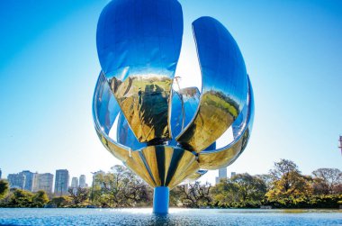 Buenos Aires, Arjantin - Plaza de las Naciones Unidas 'da yer alan Floralis Generica, sabah açık bir gökyüzü boyunca kısmen açık taç yaprakları ve tabanını kaplayan havuzu olan paslanmaz çelik ve alüminyum bir heykeldir..