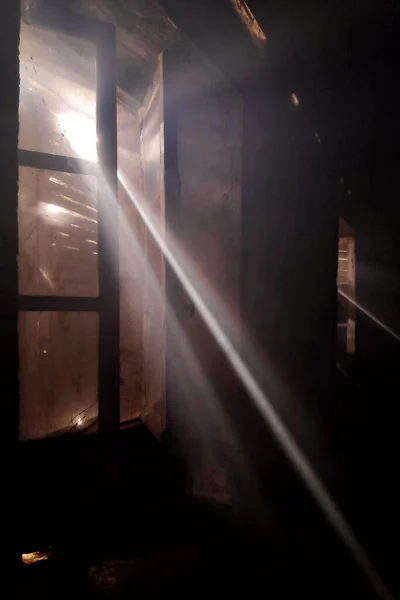 Ray of lights passing through smoky room by the broken shutters of an abandoned house.