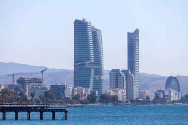 Limasol, Kıbrıs - 05 Mayıs 2025: Trilogy Limassol Seafront olarak bilinen gökdelenler ve sahil boyunca yer alan One Residential Seafront Tower, komşu binaları gölgede bıraktı..