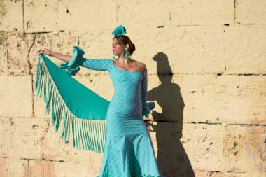 the girl with the flamenco dress in front of an old yellow wall