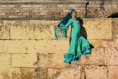 the beautiful girl in the flamenco dress dances on the stairs