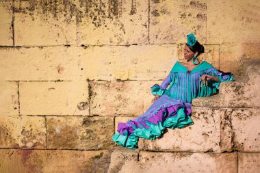 Flamenko elbiseli güzel Endülüs kadını merdivenlerde oturuyor.